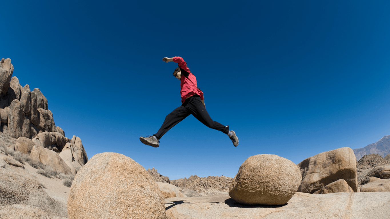 Person leaping between two boulders, symbolising the closing of the gap between AI activity and value